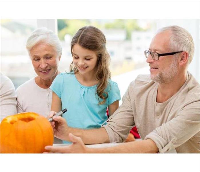 Child pumpkin carving with grandparents